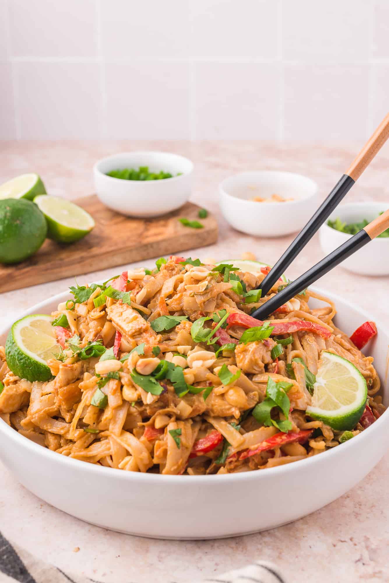 Garnished and served bowl of thai peanut noodles with chop sticks.