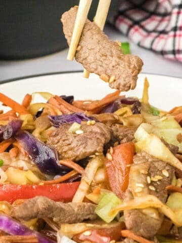 pepper steak stir fry being eaten with chop sticks.
