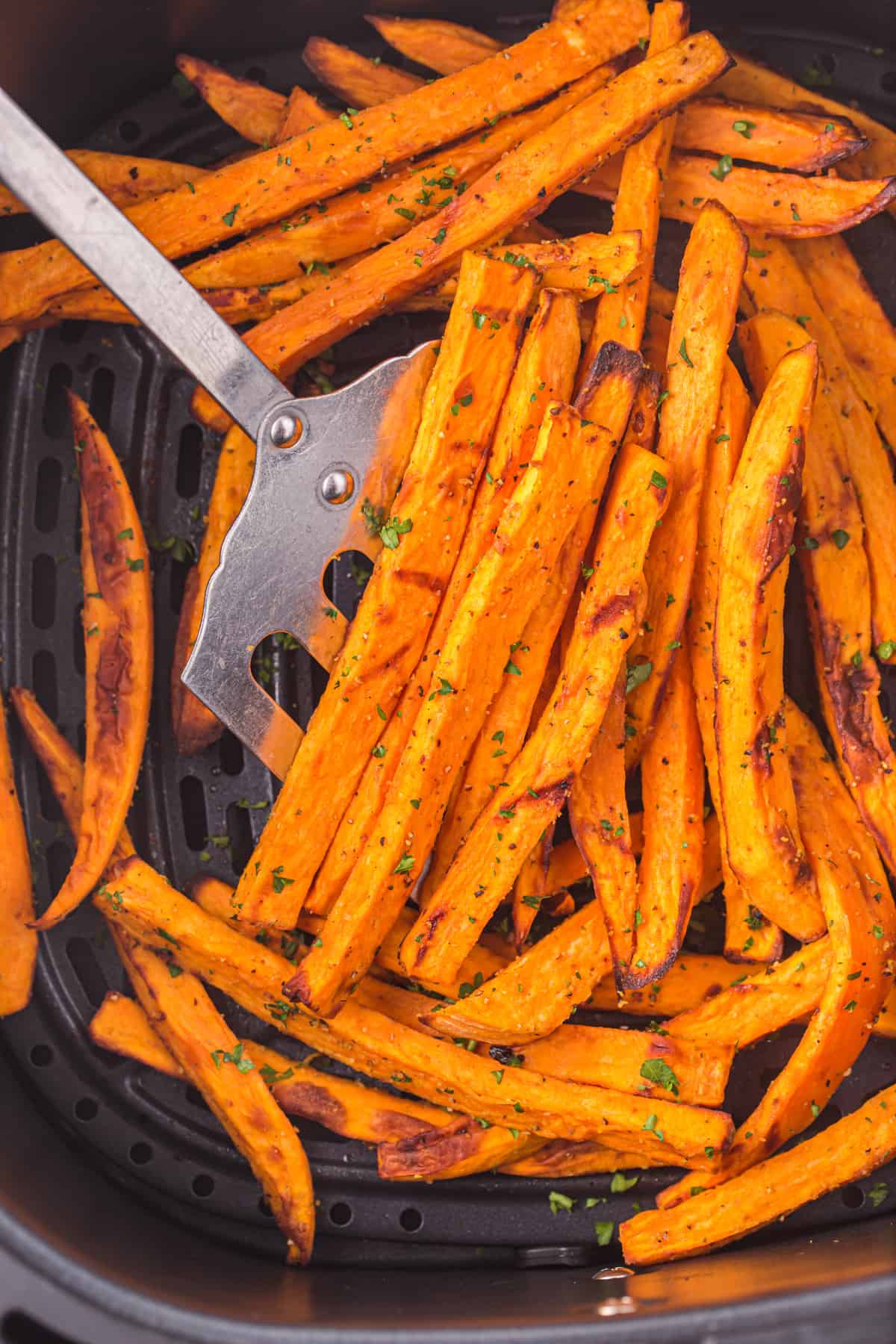 Spatula stirring sweet potato fries.