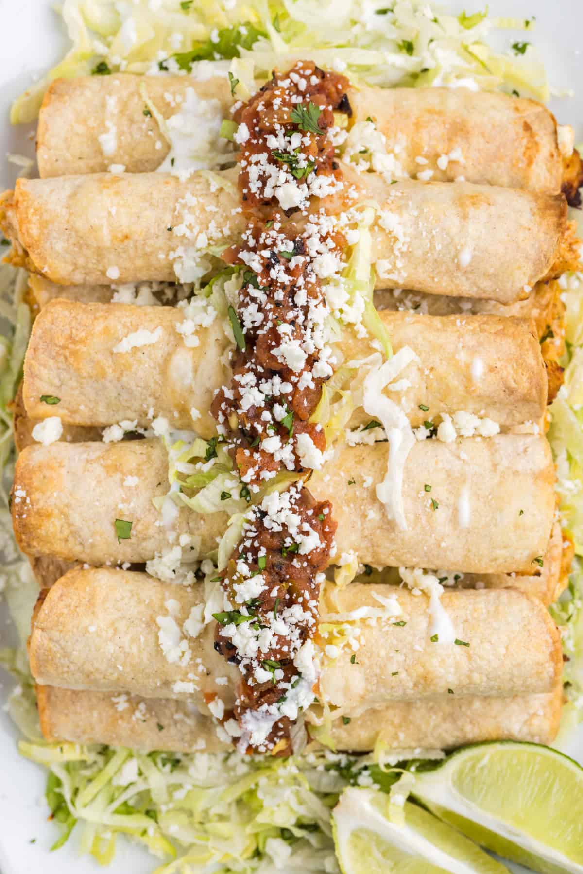 Serving taquitos with condiments on top.