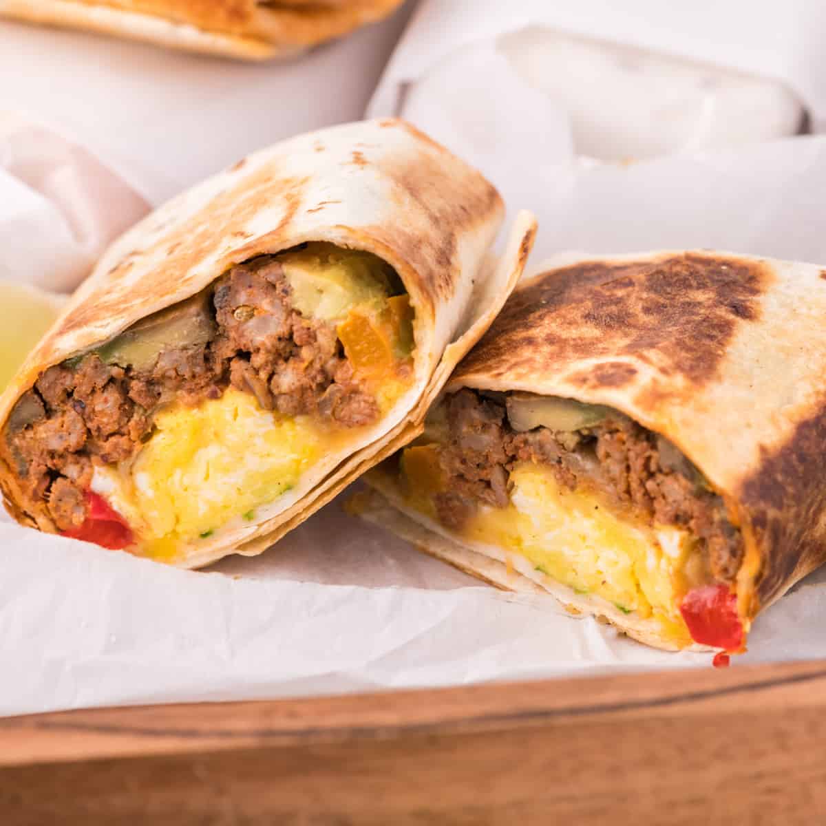 make ahead breakfast burritos cut in half showing the filling inside.