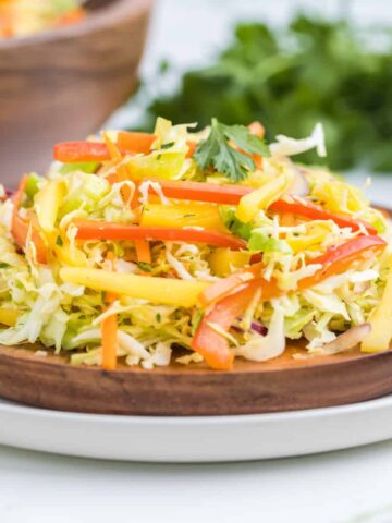 plated mango cabbage slaw on a wooden plate.