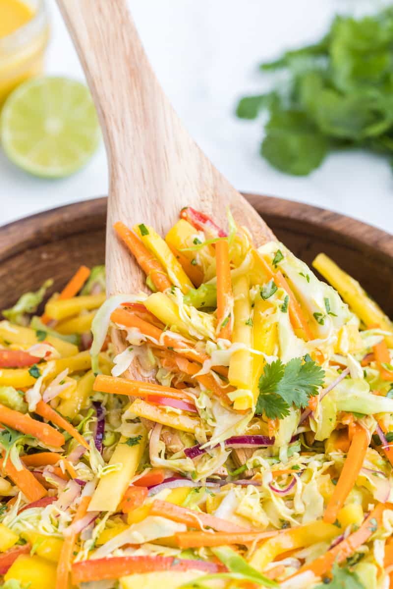 Stirring together the mango slaw with a wooden spoon.