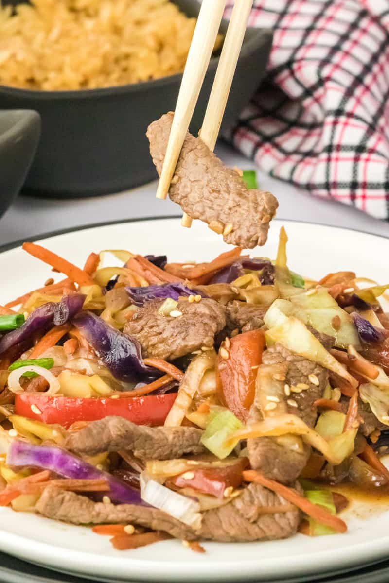 Pepper steak stir fry served and being eaten with chop sticks.