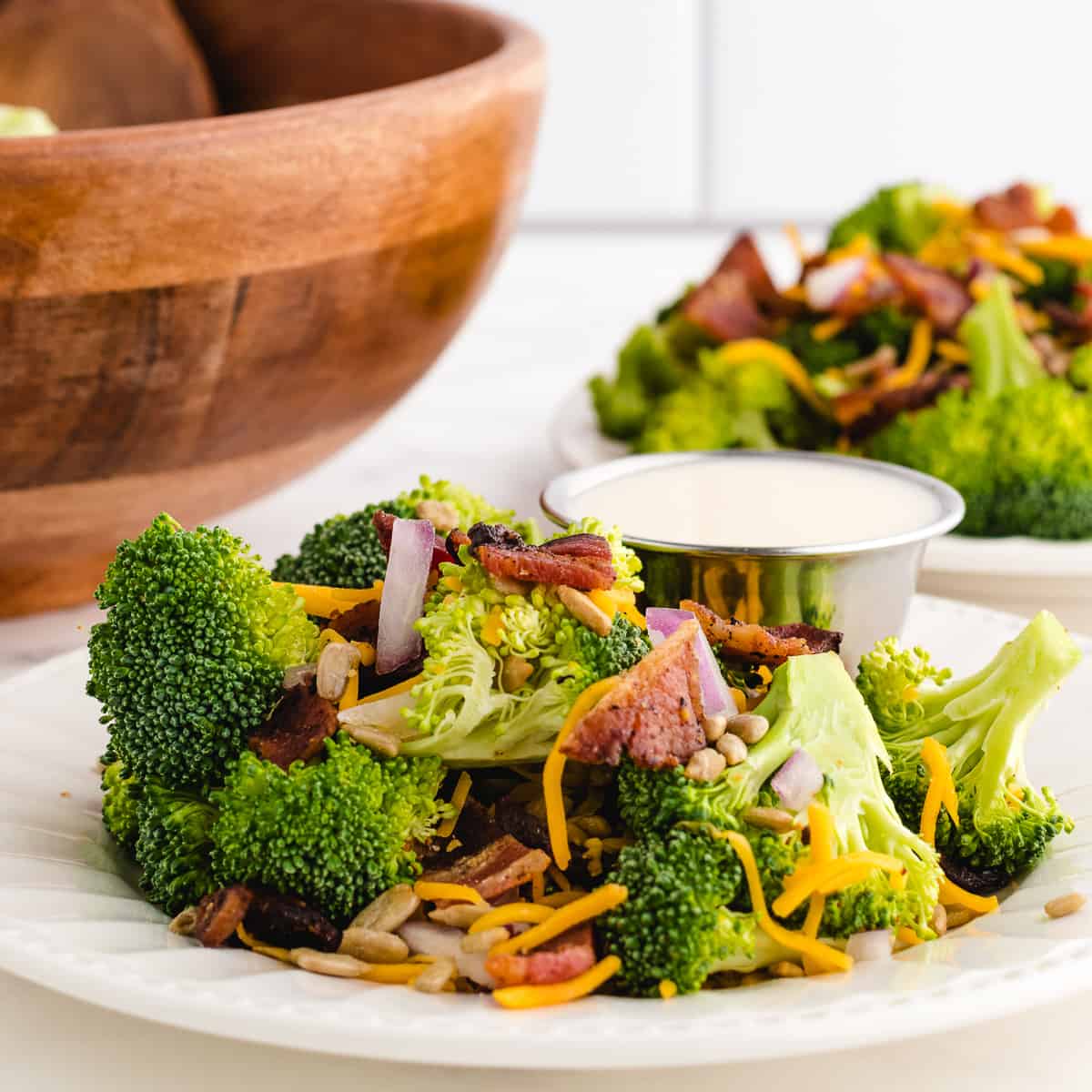 best broccoli salad on a white plate with dressing on the side