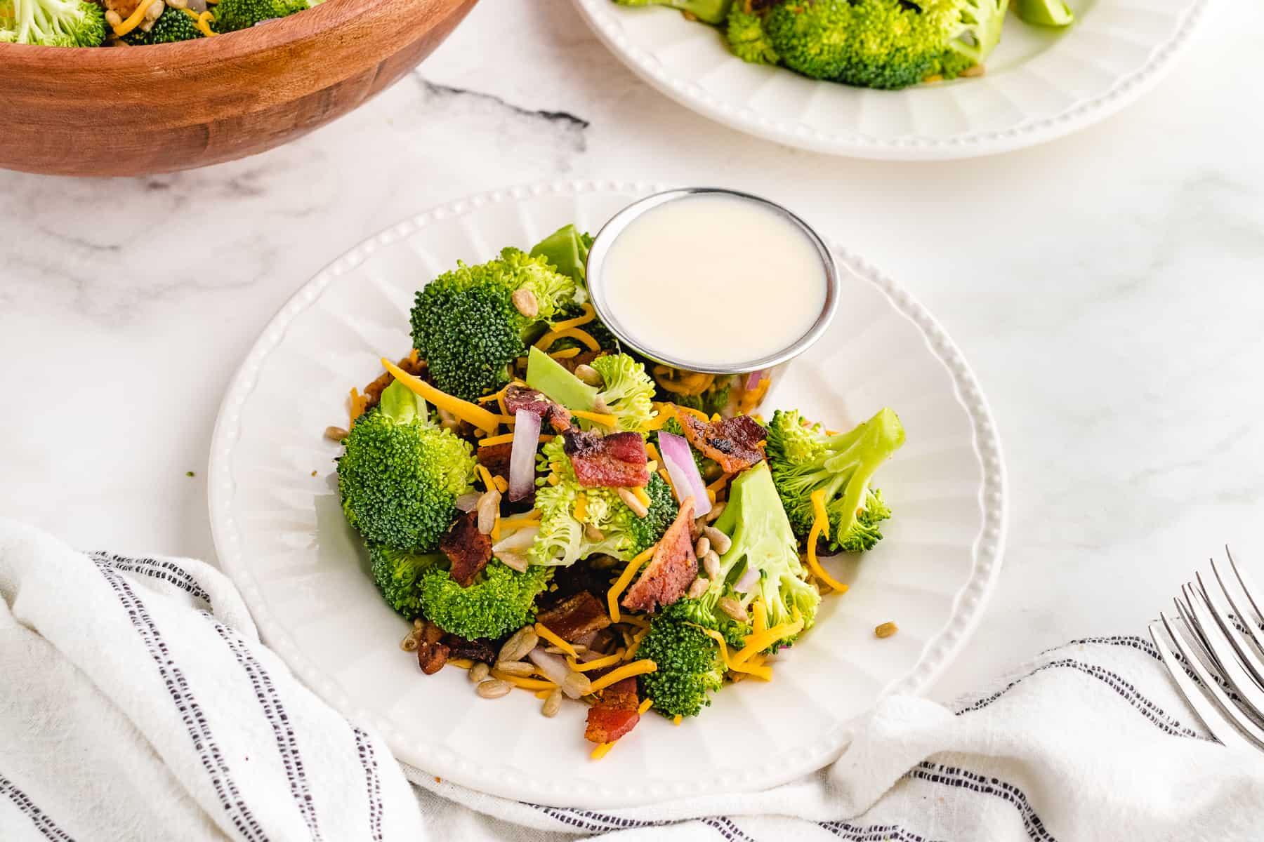 best ever broccoli salad dressing in a bowl next to raw broccoli salad