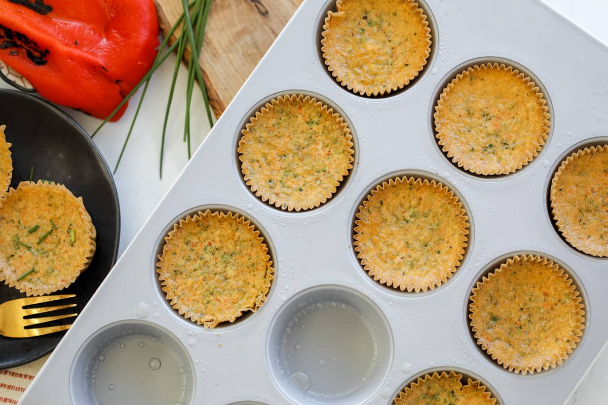 cooked egg bites in a muffin pin with some removed and set on a black plate to the side