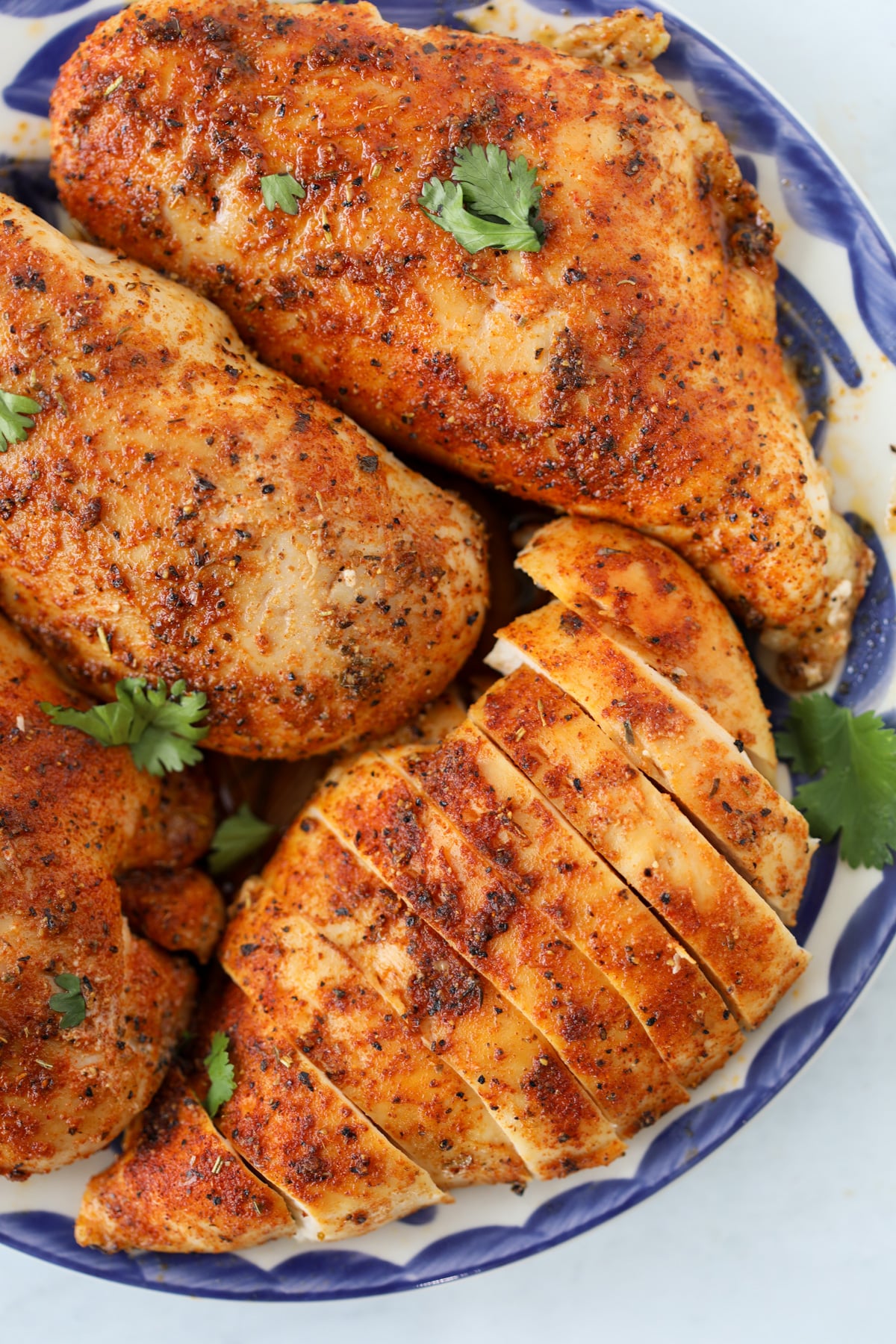 simple baked boneless skinless chicken breasts straight from the oven cooling on a blue plate