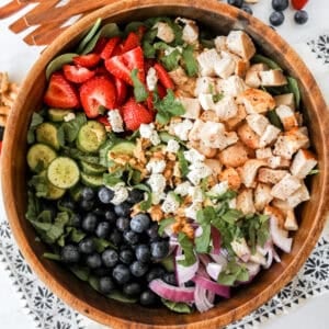 chicken strawberry salad with goat cheese and basil on a bed of baby spinach