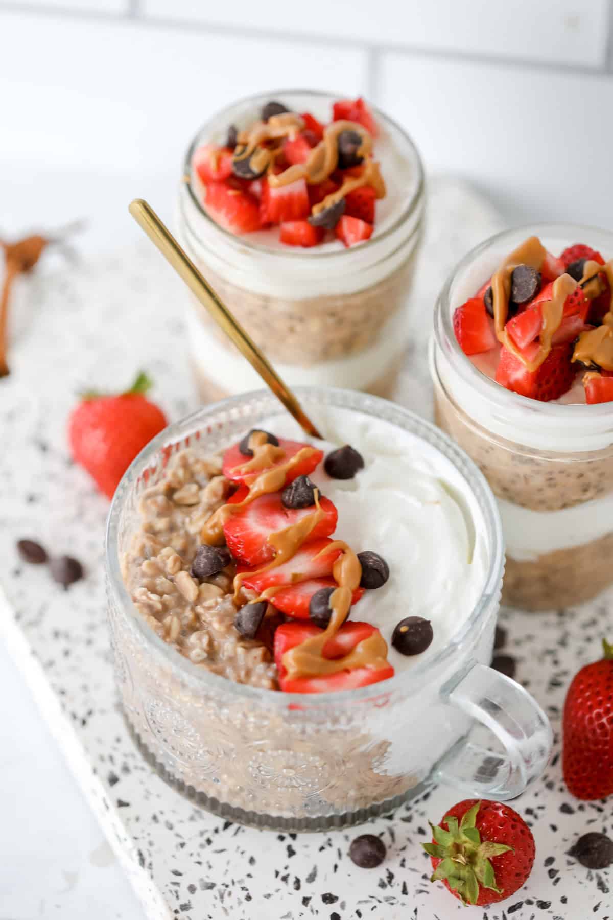 chocolate peanut butter overnight oats meal prepped in mason jars and topped with chocolate chips and strawberries