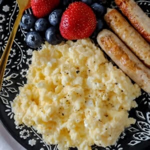 scrambled eggs with cottage cheese on a black plate after cooking in a skillet
