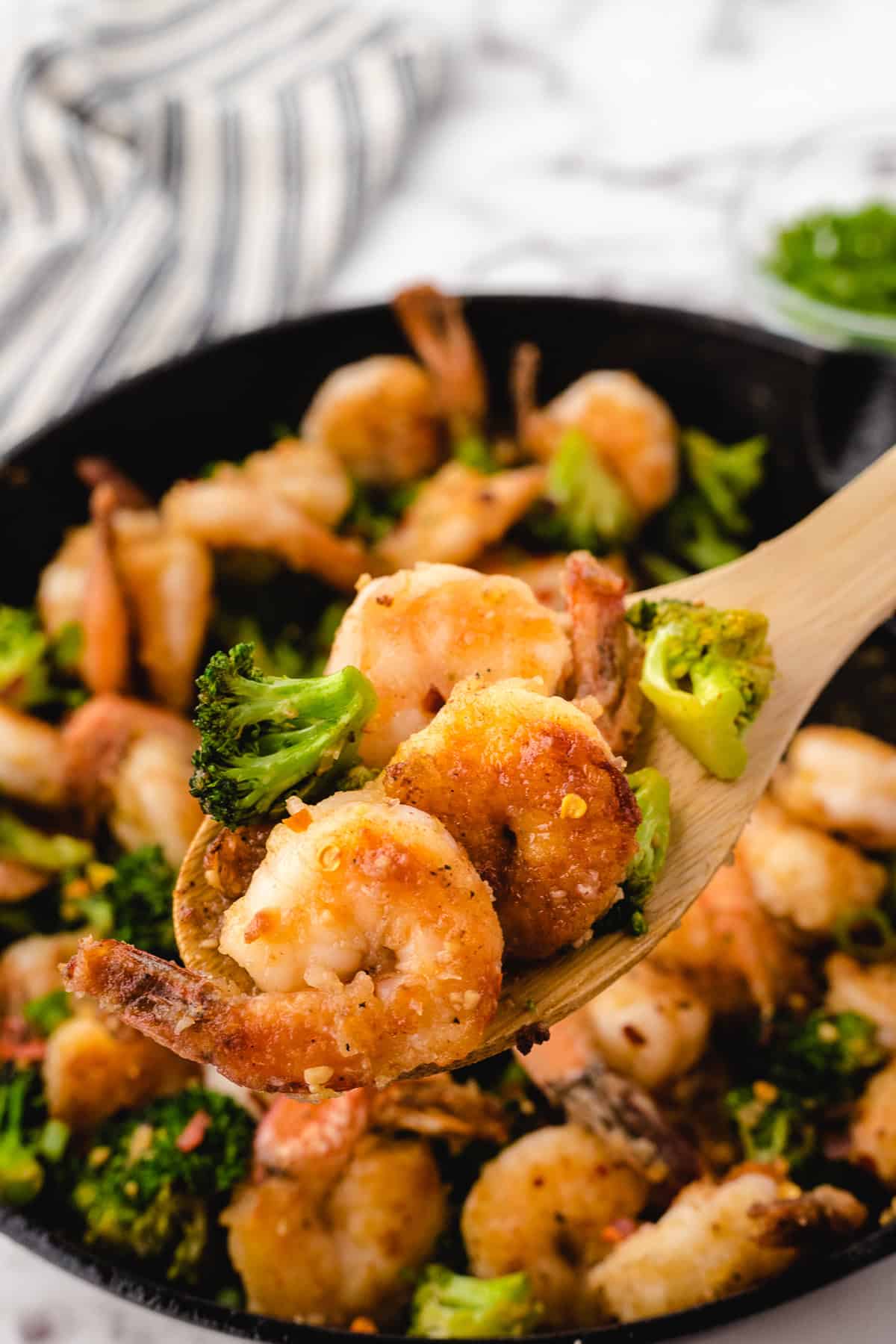 a spoonful of cooked honey garlic shrimp on a wooden spoon