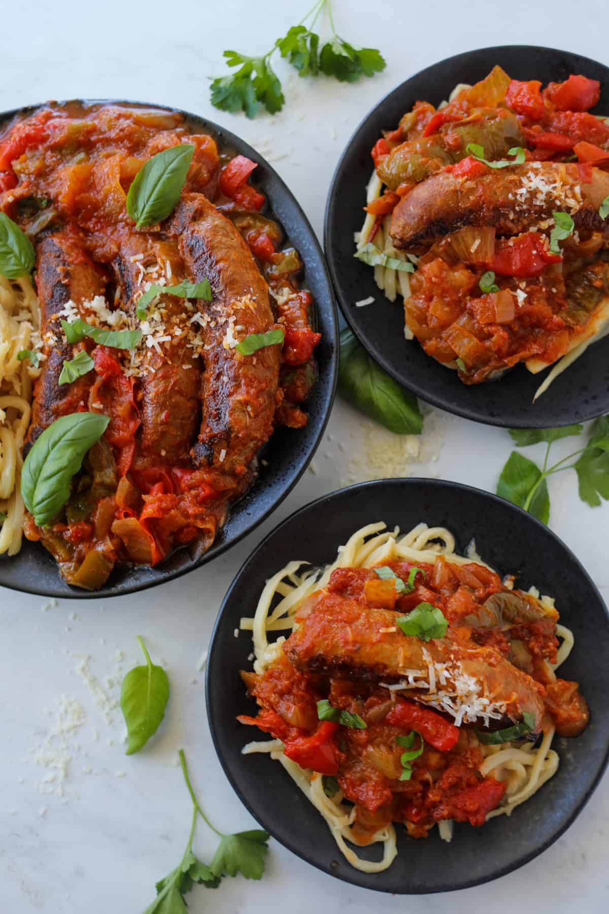 Italian chicken sausages on a black plate with bell peppers and onions