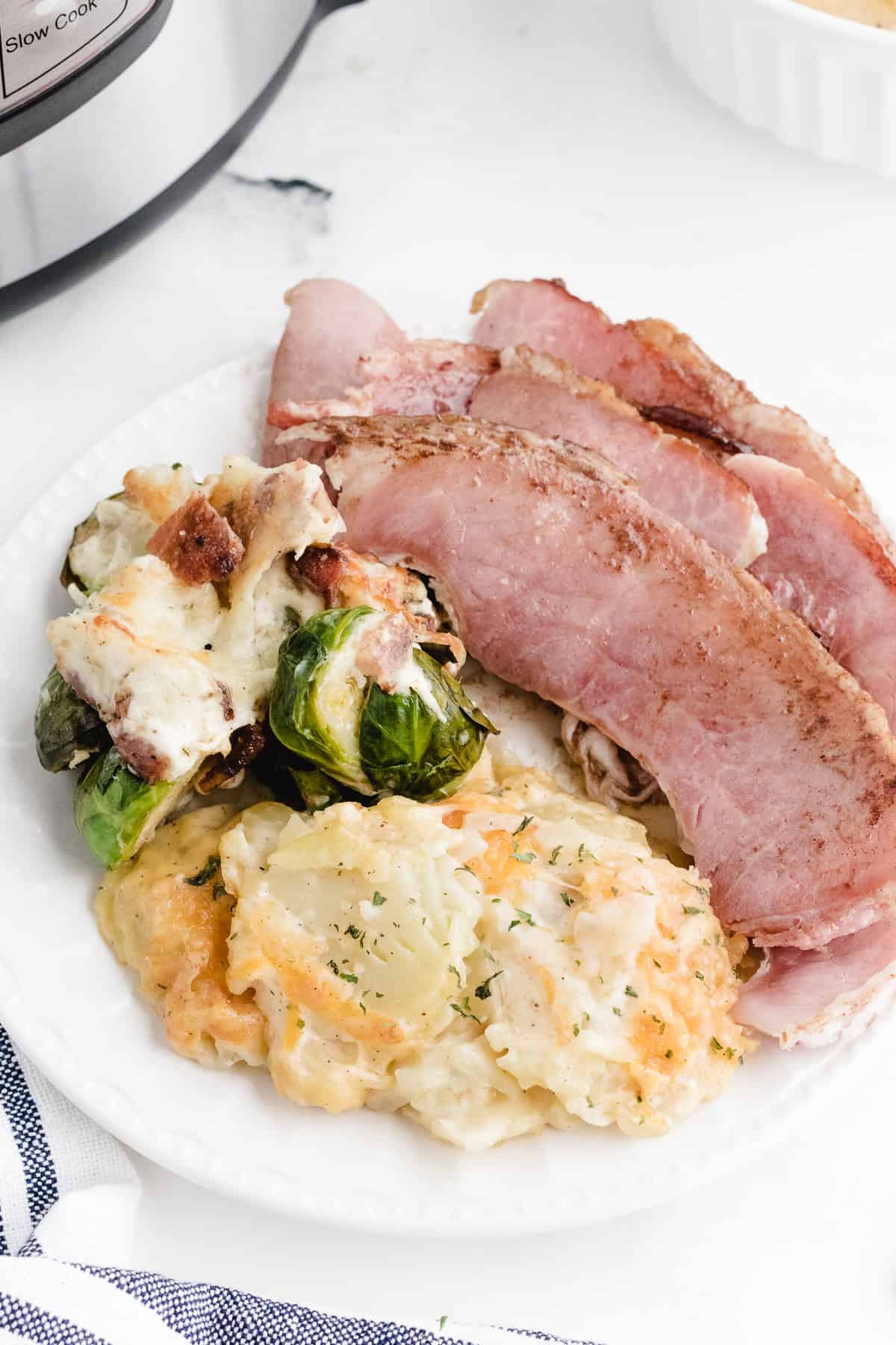 instant pot au gratin potatoes on a plate with ham and brussels sprouts