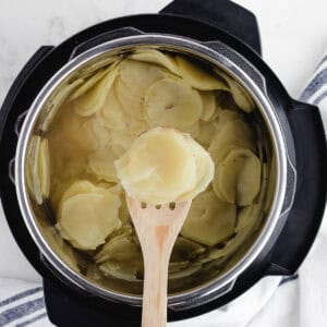 scooping sliced potatoes out of a pressure cooker
