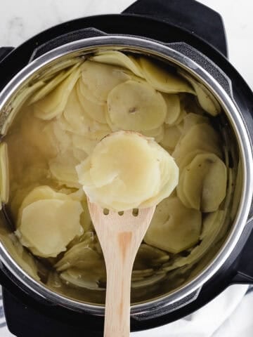 scooping sliced potatoes out of a pressure cooker