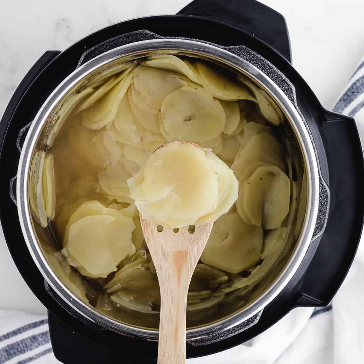 scooping sliced potatoes out of a pressure cooker