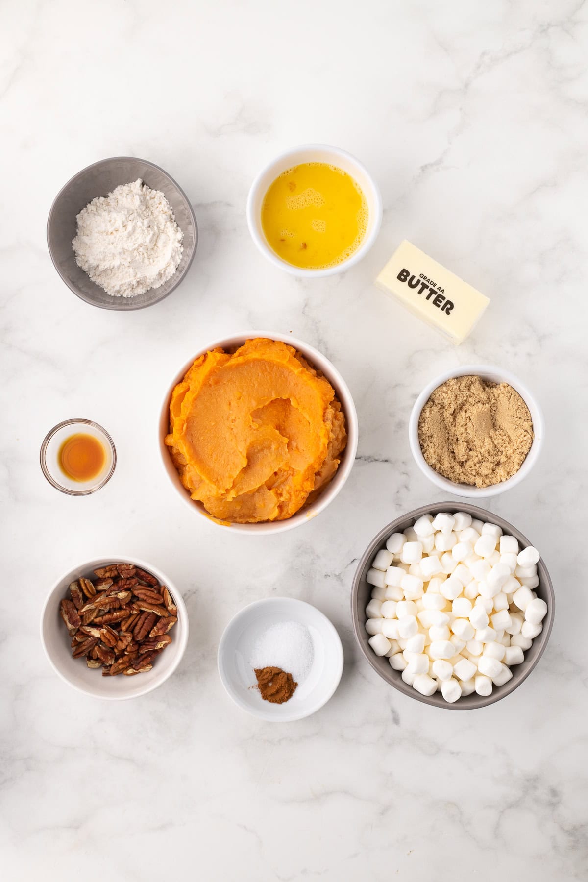 ingredients for sweet potato casserole with canned sweet potatoes and marshmallows on a white cutting board