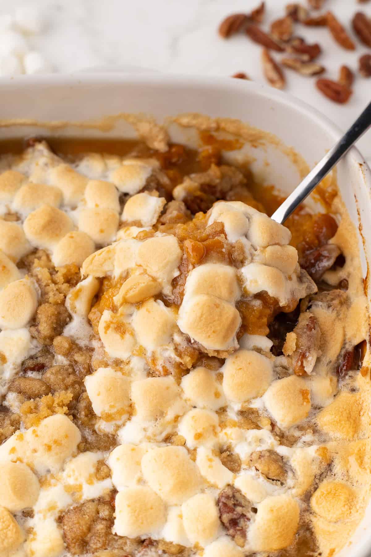 taking a bite spoonful of sweet potato casserole with marshmallows on top