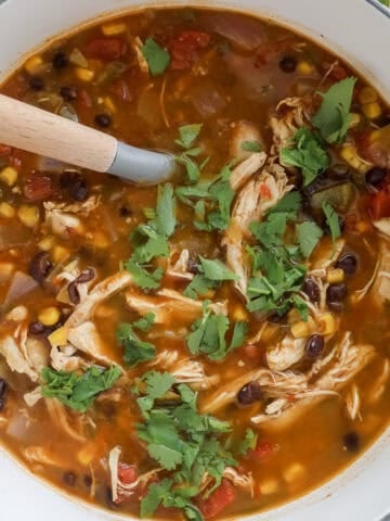the cooked taco soup on a cutting board with shredded chicken and cilantro on top