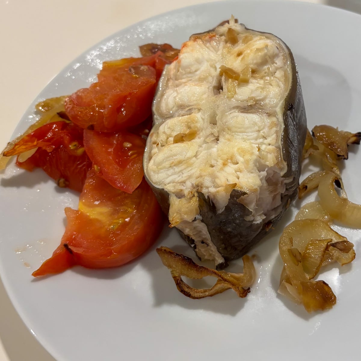 baked eel on a plate with onions and tomatoes