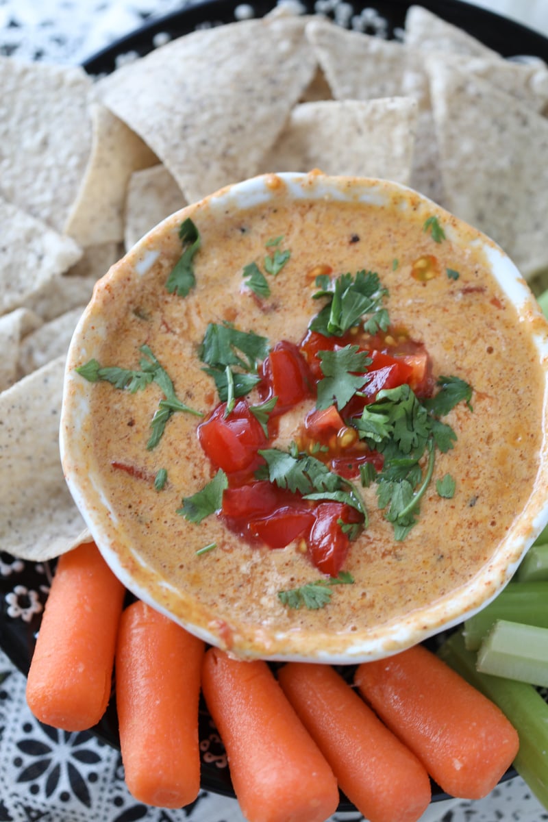 queso dip with cottage cheese in a white bowl with veggie sticks and tortilla chips