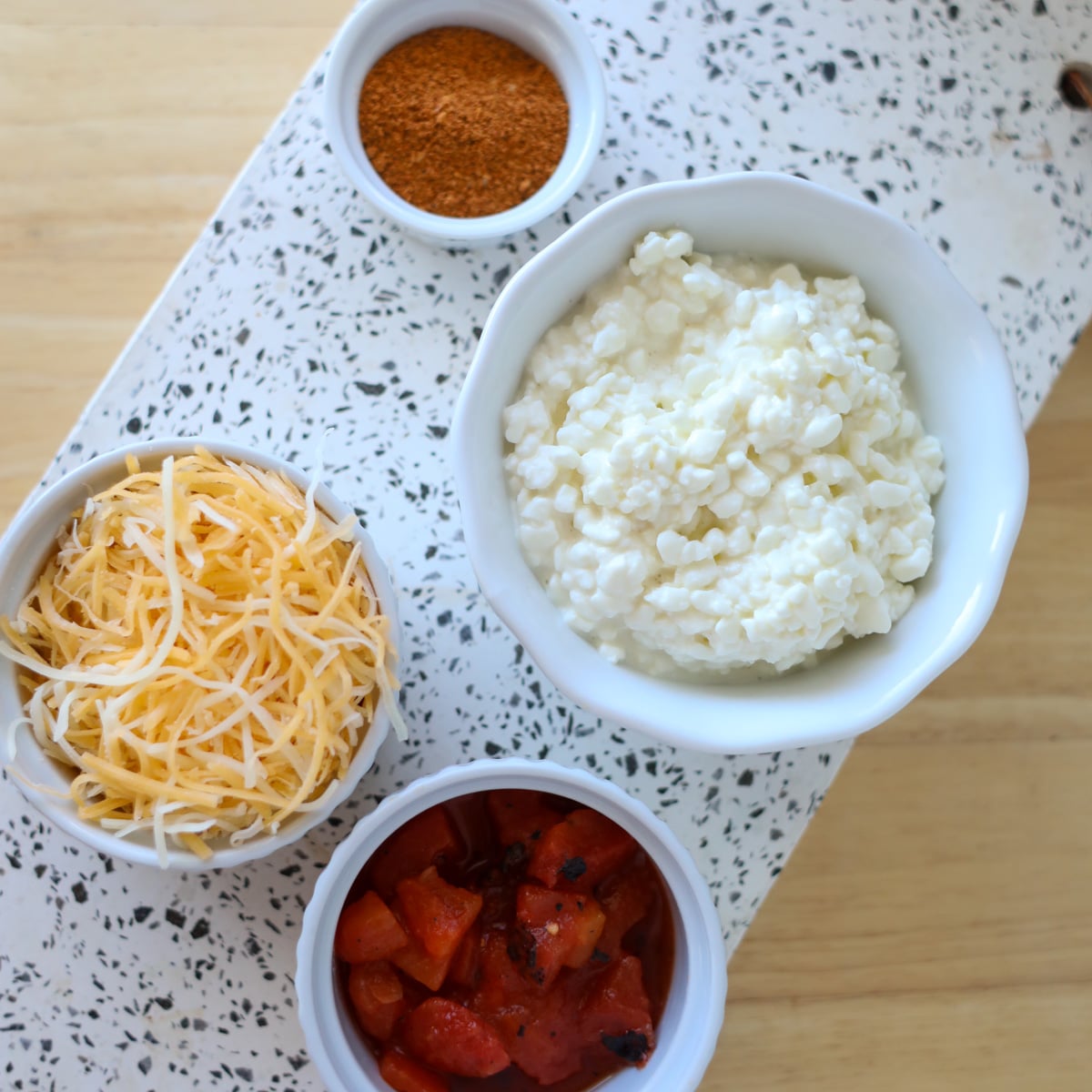 cottage cheese rotel taco seasoning and shredded cheese on a white cutting board