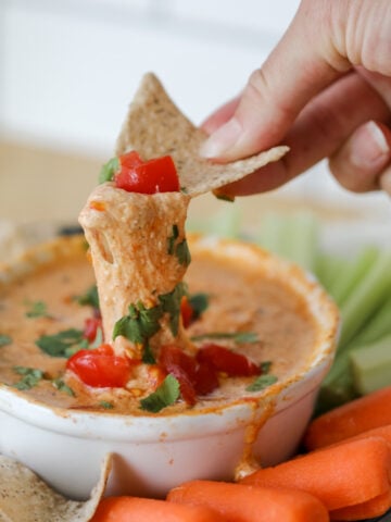 queso dip with cottage cheese in a white bowl with vegetable sticks