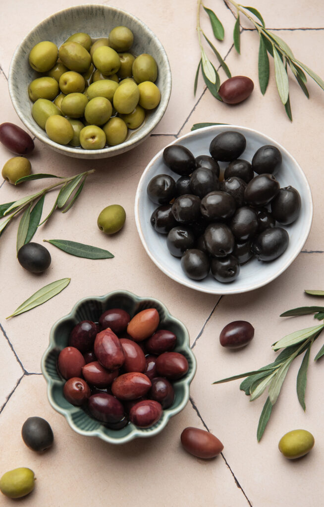 olives in small bowls on a light pink background