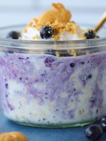 berry cheesecake overnight oats with frozen blueberries mixed in