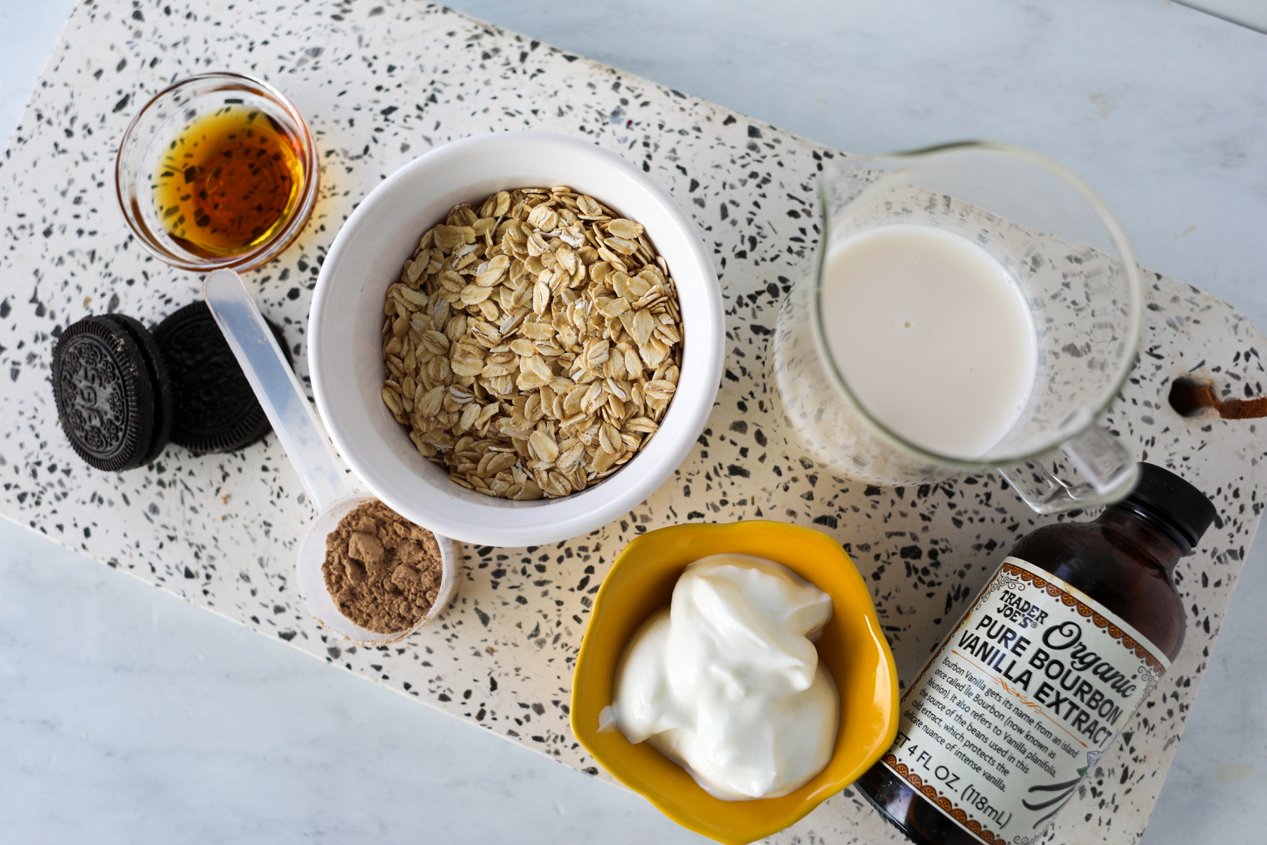 ingredients in high protein cookies and cream overnight oats on a white marble board