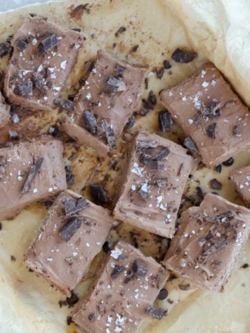 cottage cheese fudge cut up on parchment paper sprinkled with chopped dark chocolate and sea salt