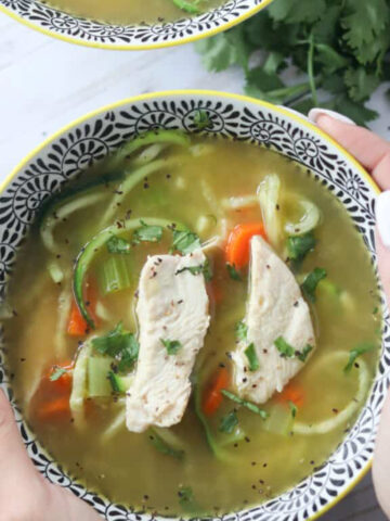 chicken noodle soup without noodles in a bowl with rotisserie chicken zucchini noodles carrots and celery