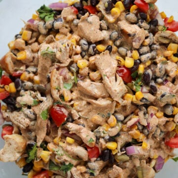 pouring the dressing over the southwest salad with chicken