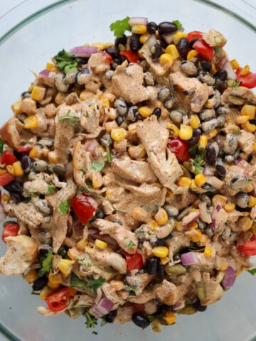 pouring the dressing over the southwest salad with chicken