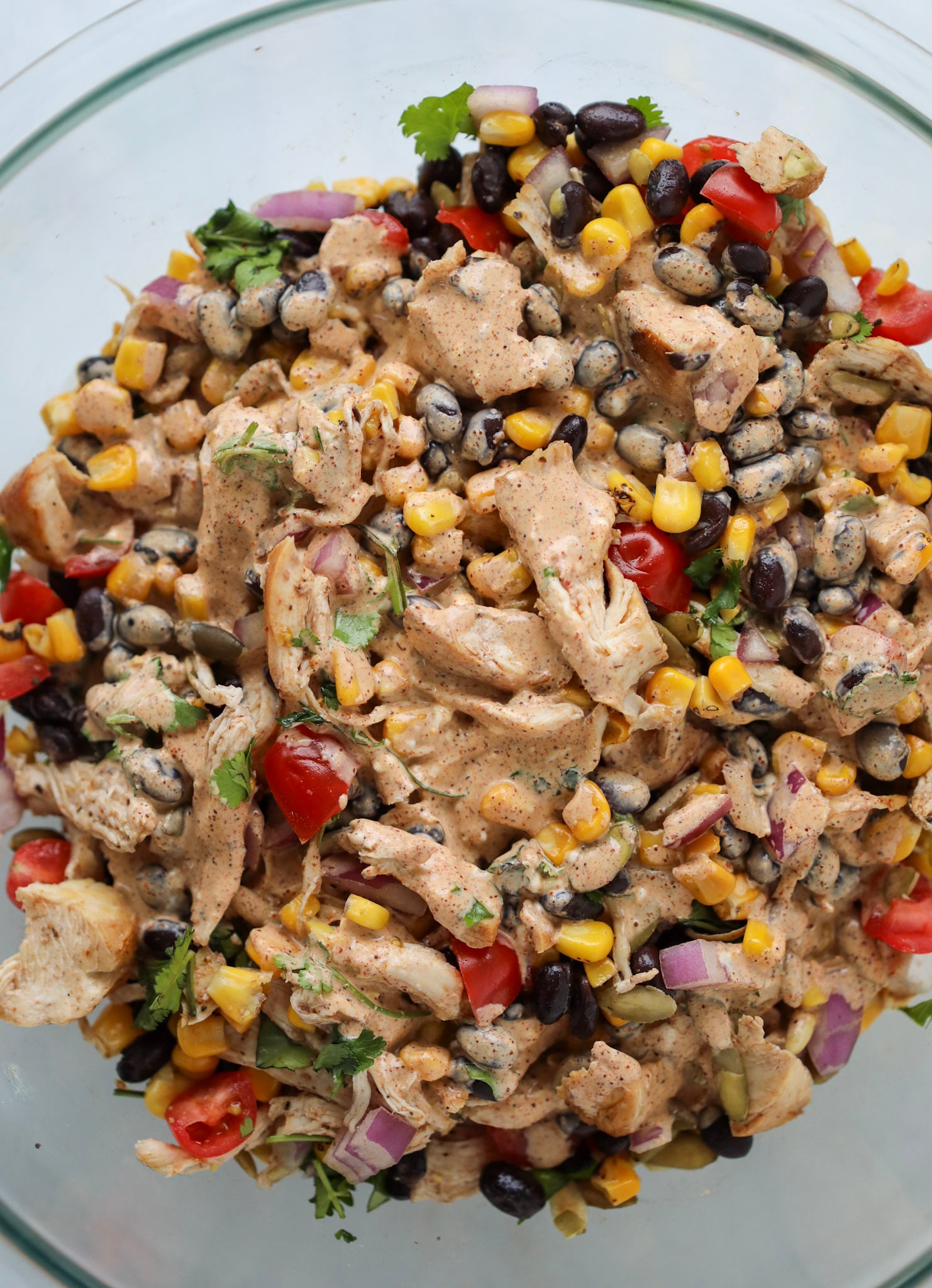 the southwest chicken salad in a clear glass mixing bowl all mixed together