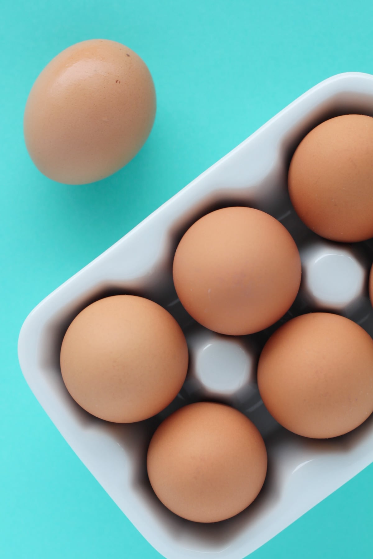 instant pot hard boiled eggs in a ceramic egg carton on a blue background