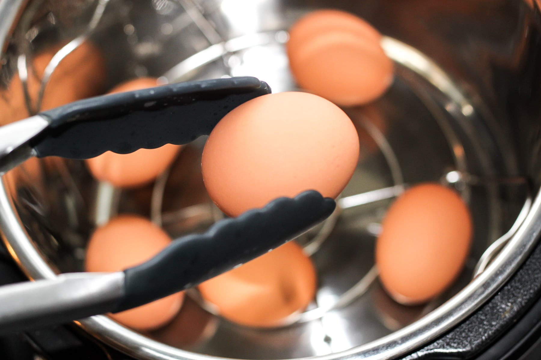 removing the instant pot 555 eggs from the pressure cooker rack with tongs
