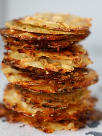 crispy cottage cheese chips stacked on a white plate