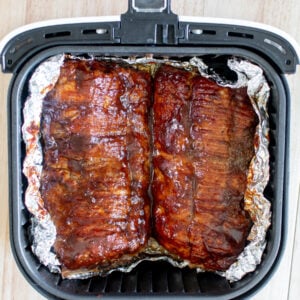 easy air fryer baby back ribs sprinkled with dry rub and brushed with bbq sauce