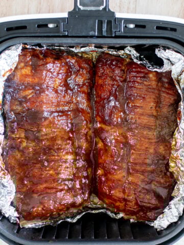 easy air fryer baby back ribs sprinkled with dry rub and brushed with bbq sauce