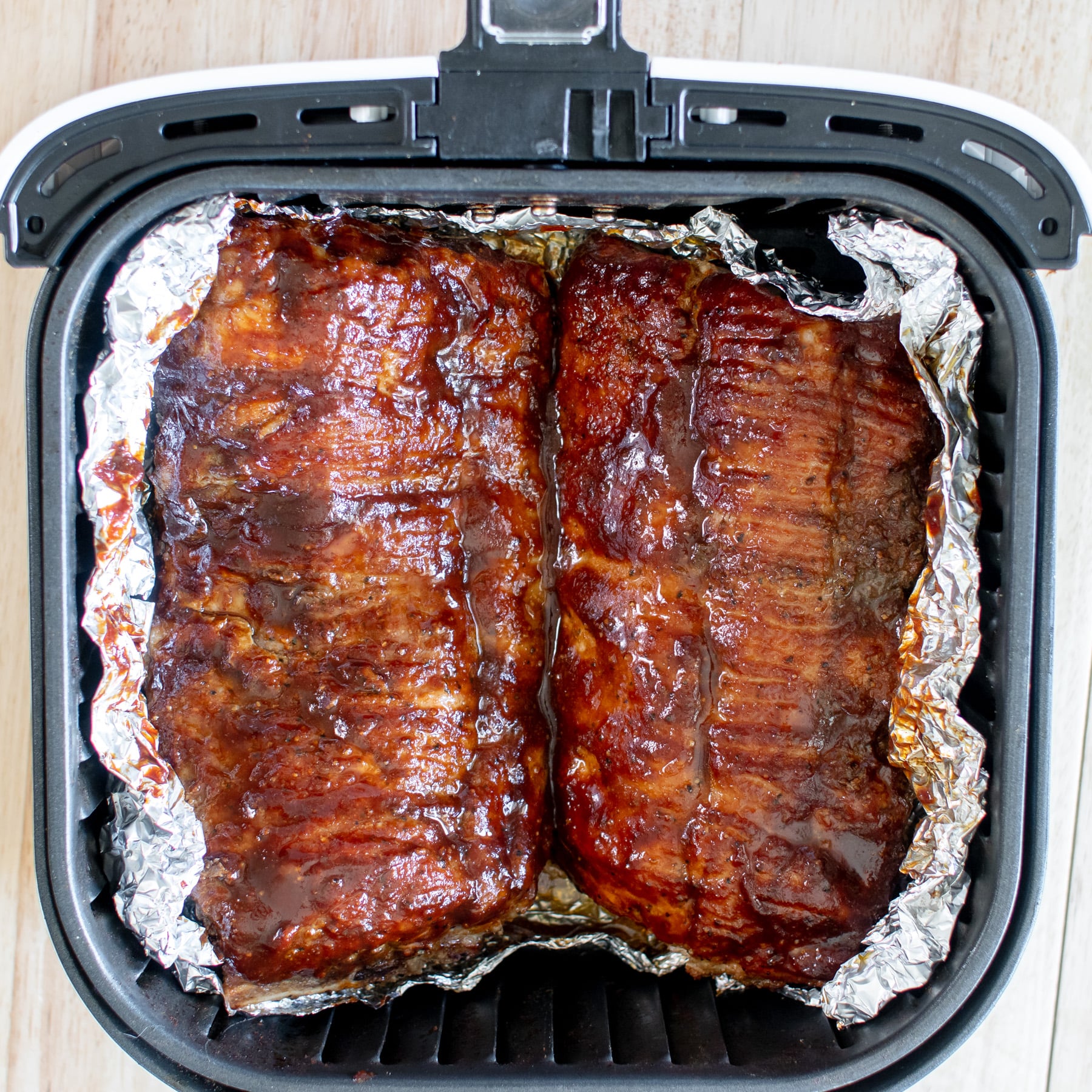 easy air fryer baby back ribs sprinkled with dry rub and brushed with bbq sauce