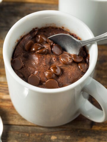 chocolate mug cake with protein powder in a white mug and a spoon with in the cake
