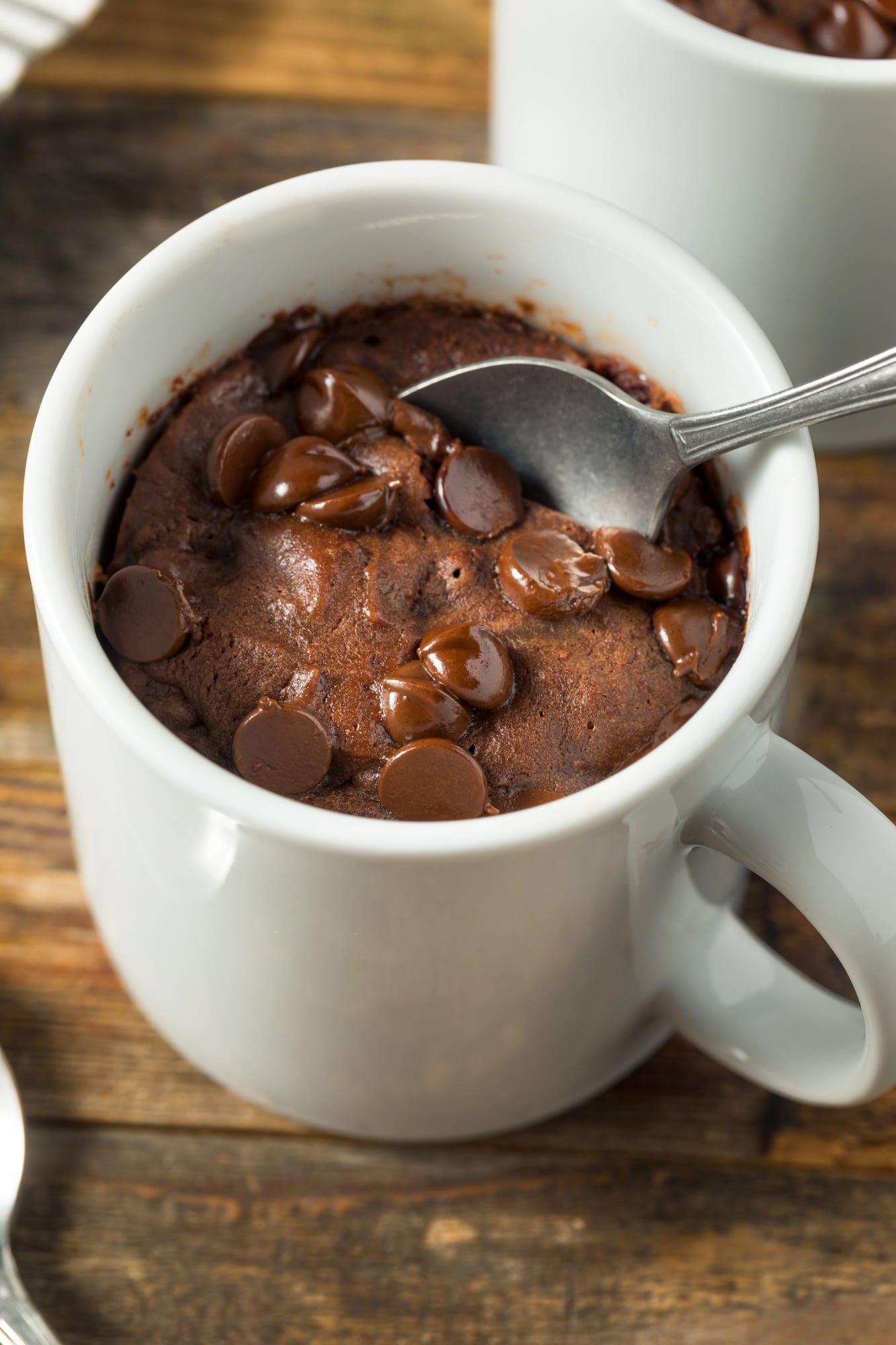 chocolate mug cake with protein powder in a white mug and a spoon with in the cake