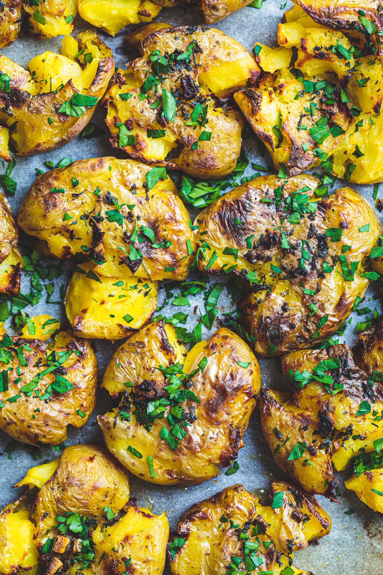 smashed potatoes on the blackstone golden and crispy garnished with fresh parsley
