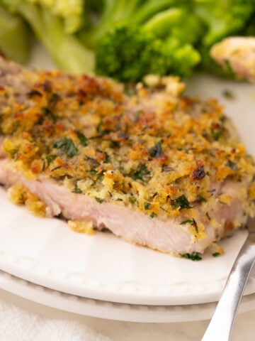 air fryer bone in breaded pork chops that are thin cut on a white plate with broccoli