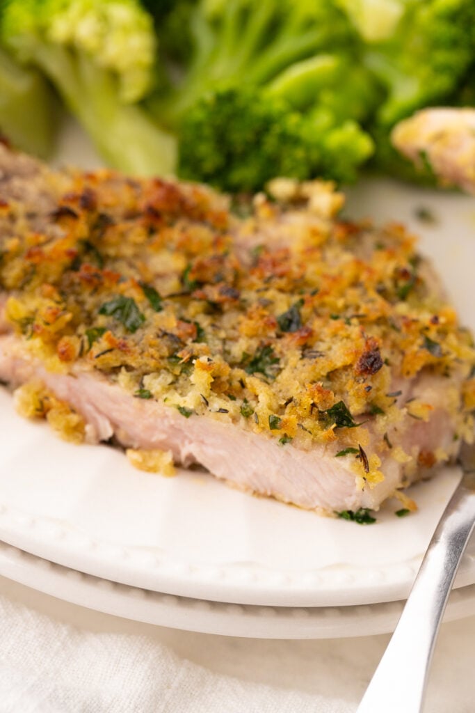air fryer bone in breaded pork chops that are thin cut on a white plate with broccoli
