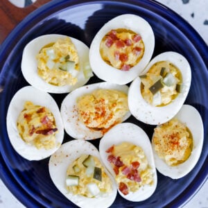 zero carb deviled eggs topped with bacon pickles and paprika on a blue plate