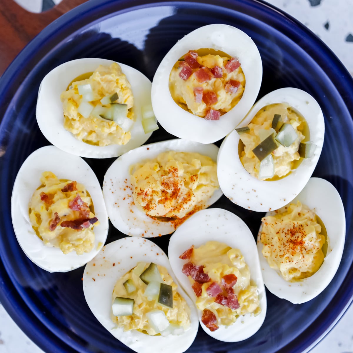zero carb deviled eggs topped with bacon pickles and paprika on a blue plate