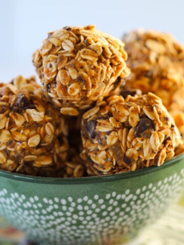 healthy pumpkin protein balls with rolled oats and protein powder stacked up in a green bowl